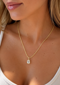 Model wearing a gold teardrop cubic zirconia pendant necklace on a delicate gold chain.