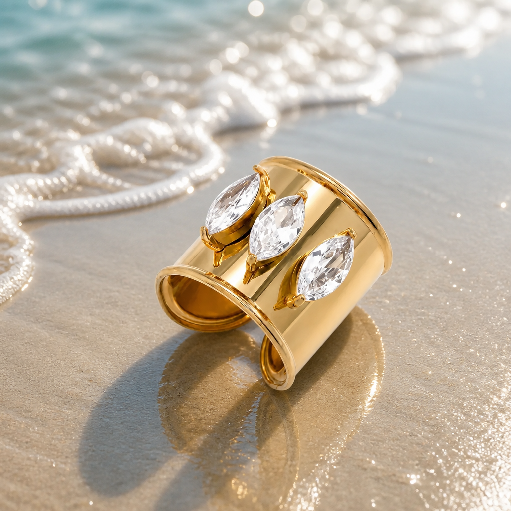 Bali Ring featuring three marquise-cut cubic zirconia stones in an adjustable 18k gold-plated stainless steel band on a sandy beach.