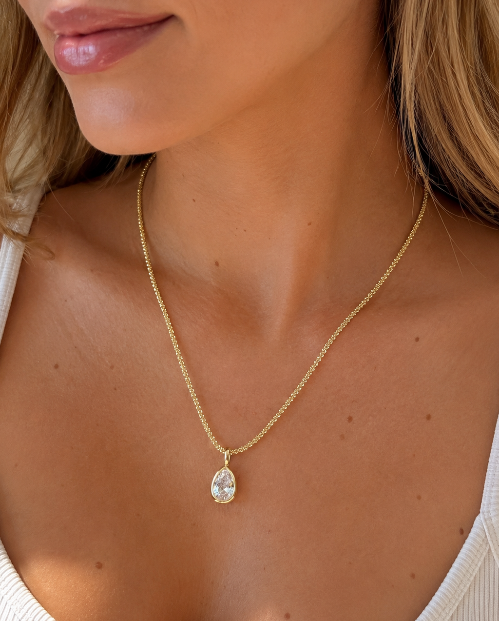Close-up of a 14k gold-plated sterling silver chain styled with a crystal pendant.