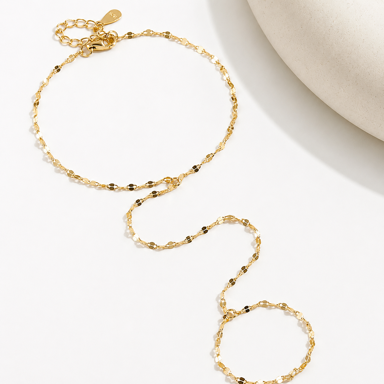 Fingerling Bracelet displayed flat on a white surface showing the adjustable 14k gold plated hand chain design.