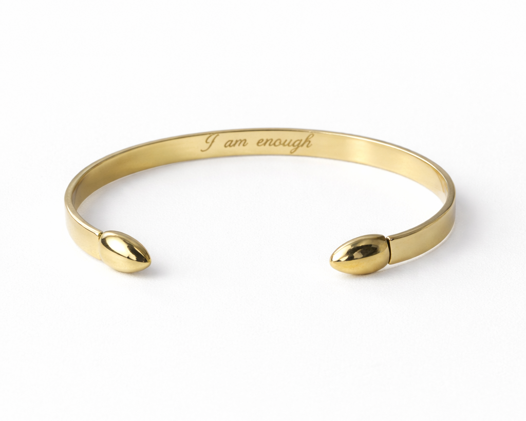 Gold bracelet with 'I am enough' engraving on a white background