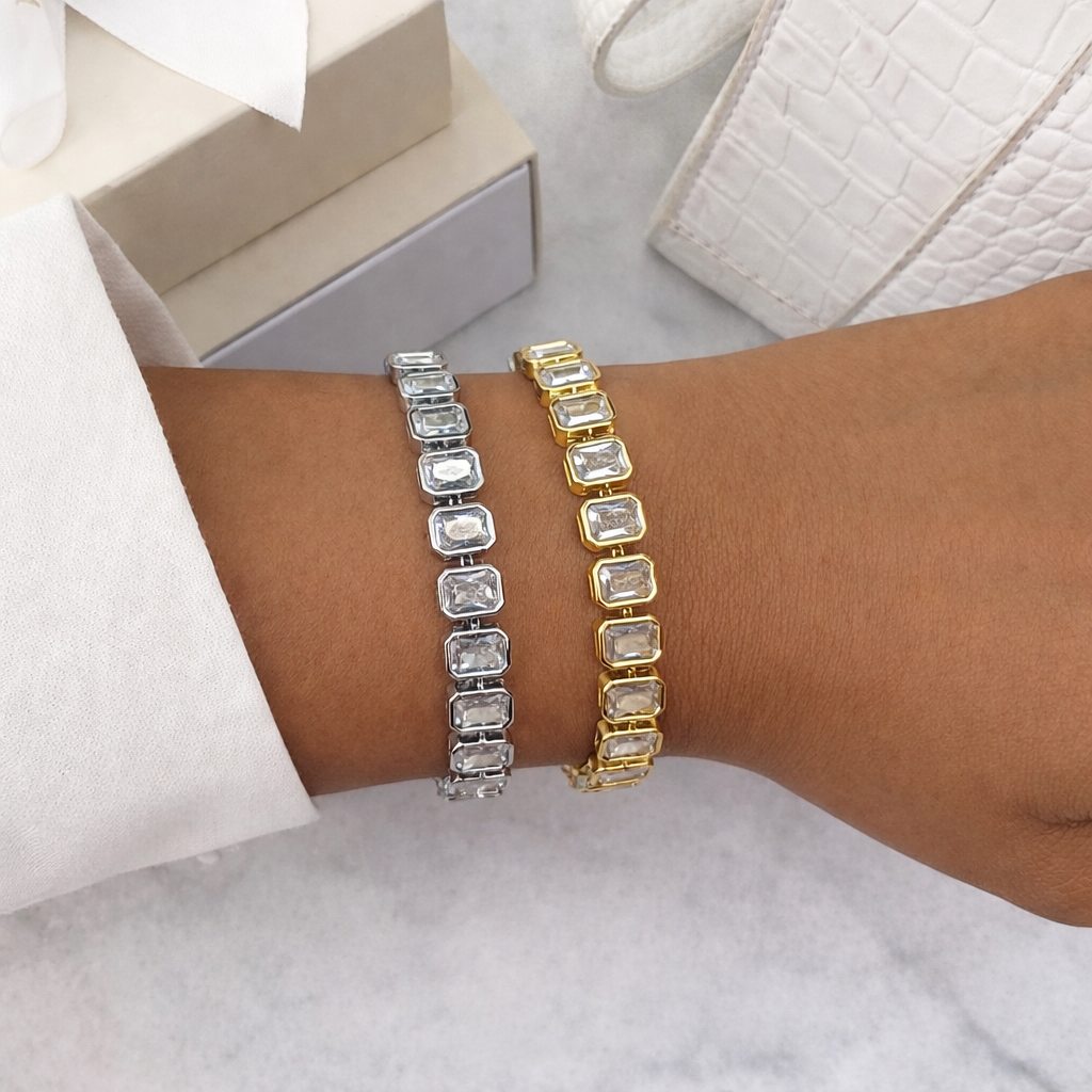 Two bracelets, one silver and one gold, on a wrist with a neutral background.