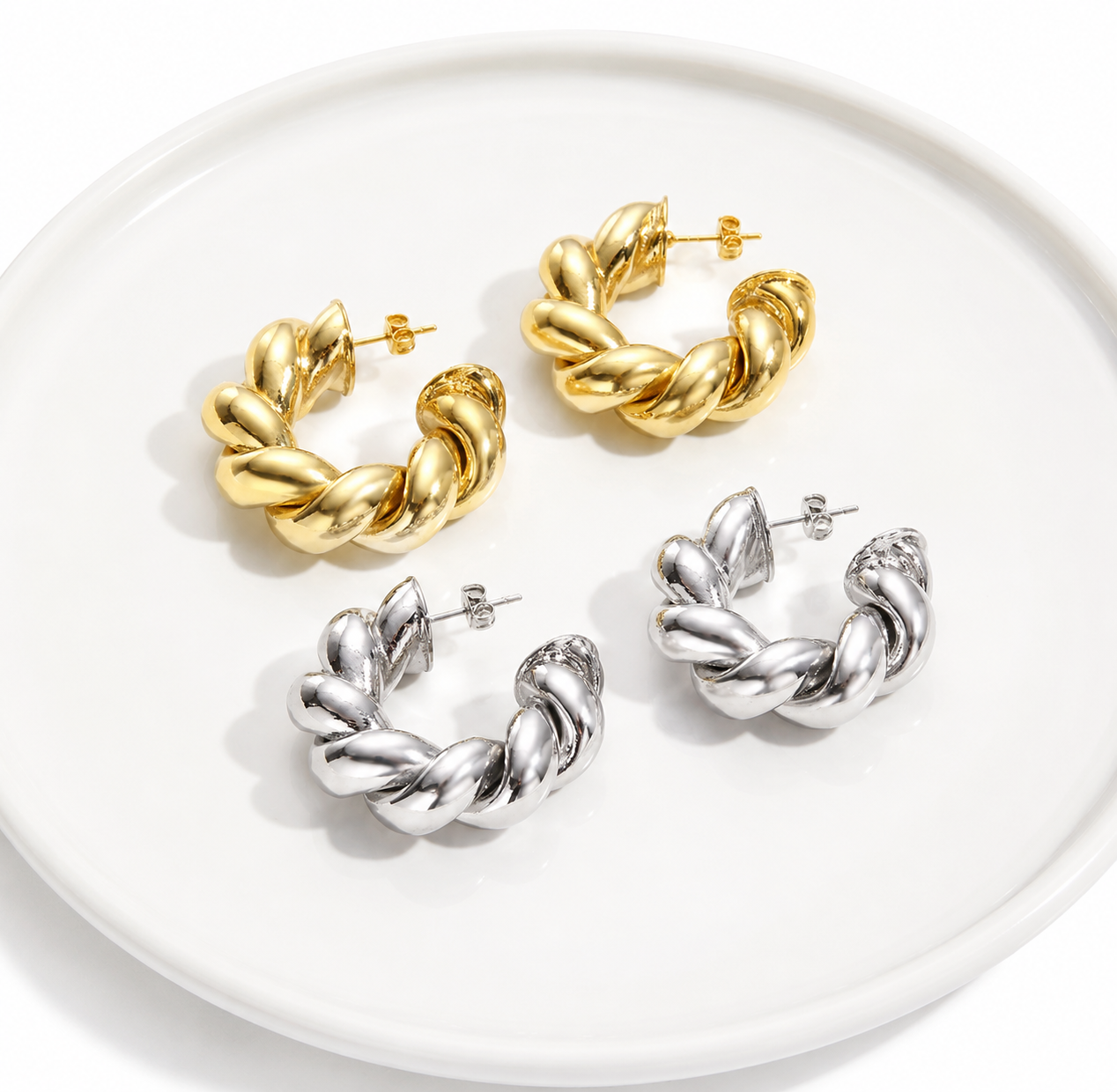 Close-up of chunky twisted hoop earrings showing polished texture and curved design.