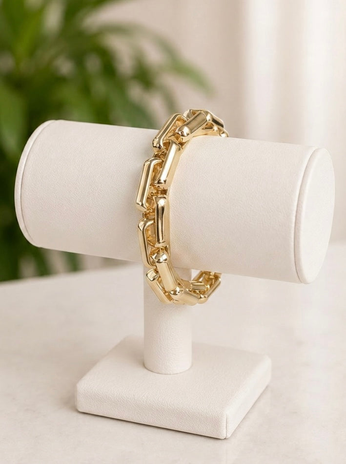 Cooper Bracelet in 14 karat gold plating displayed on a white jewellery stand, featuring polished rectangular stretch links.