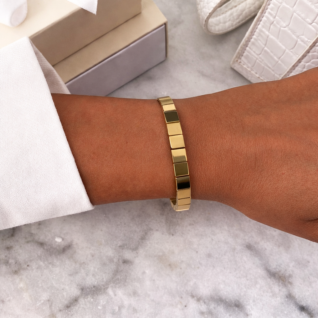 Gold bracelet on a wrist with a marble surface and box in the background