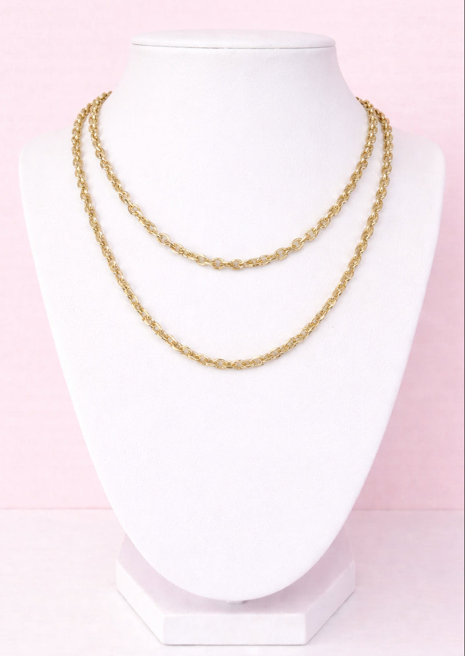 Gold chain necklace on a mannequin against a pink background