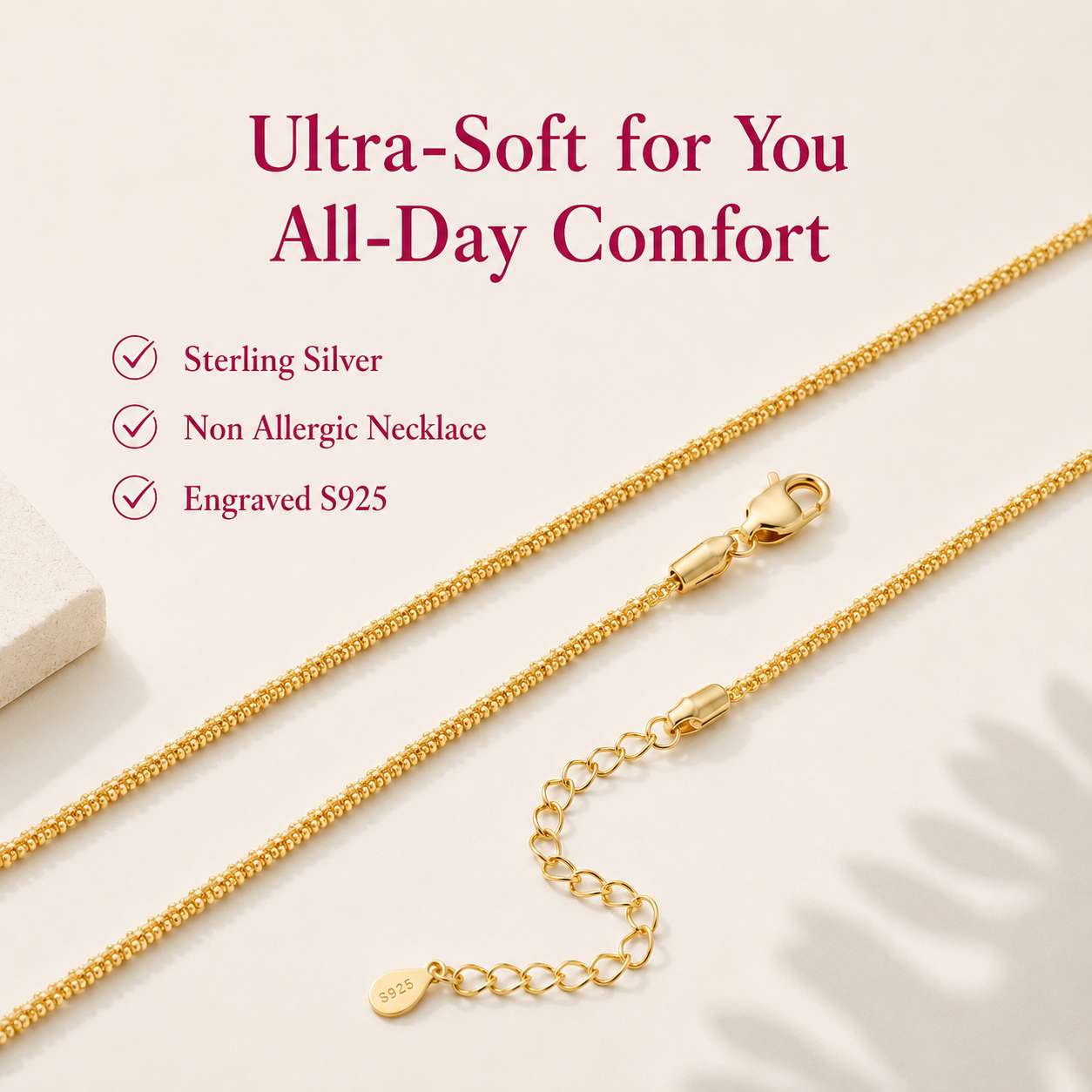 A close-up of a gold-tone chain necklace with a lobster clasp and extender chain on a light beige background, with marketing text reading 'Ultra-Soft for You All-Day Comfort' and bullet points for Sterling Silver, Non Allergic Necklace, and Engraved S925.