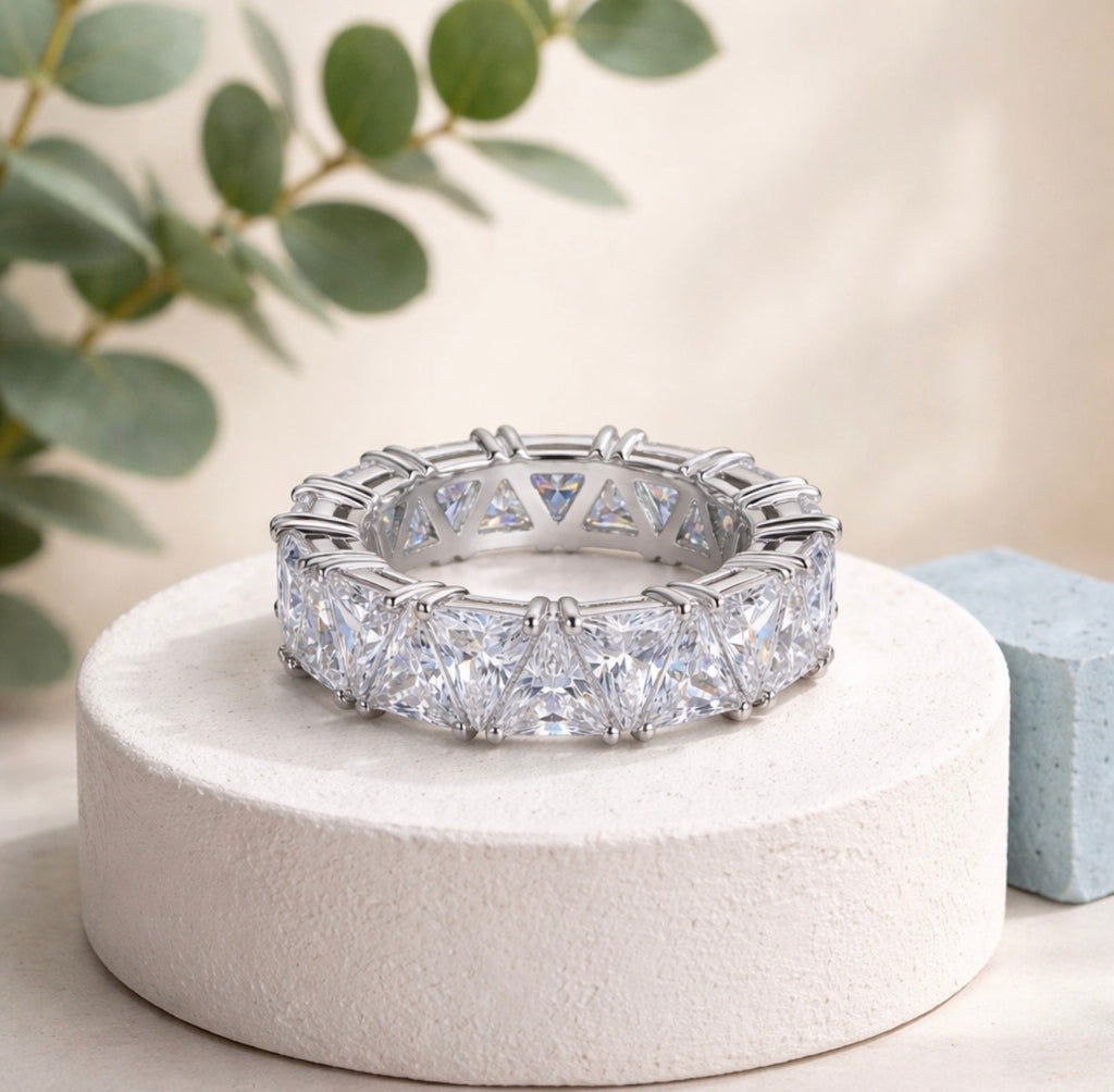 Maya Ring displayed on a white jewellery pedestal with clear triangular-cut stones and a polished silver-tone finish.