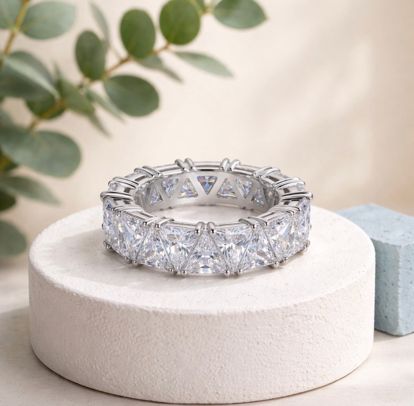 Maya Ring displayed on a white jewellery pedestal with clear triangular-cut stones and a polished silver-tone finish.
