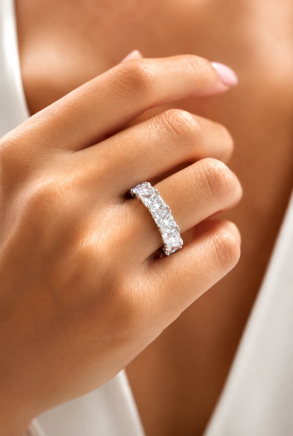 Model wearing the Maya Ring, a silver-tone eternity ring with sparkling triangular-cut clear stones.