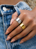 Close-up of gold wide band ring cuff worn on finger with polished mirror-like finish.