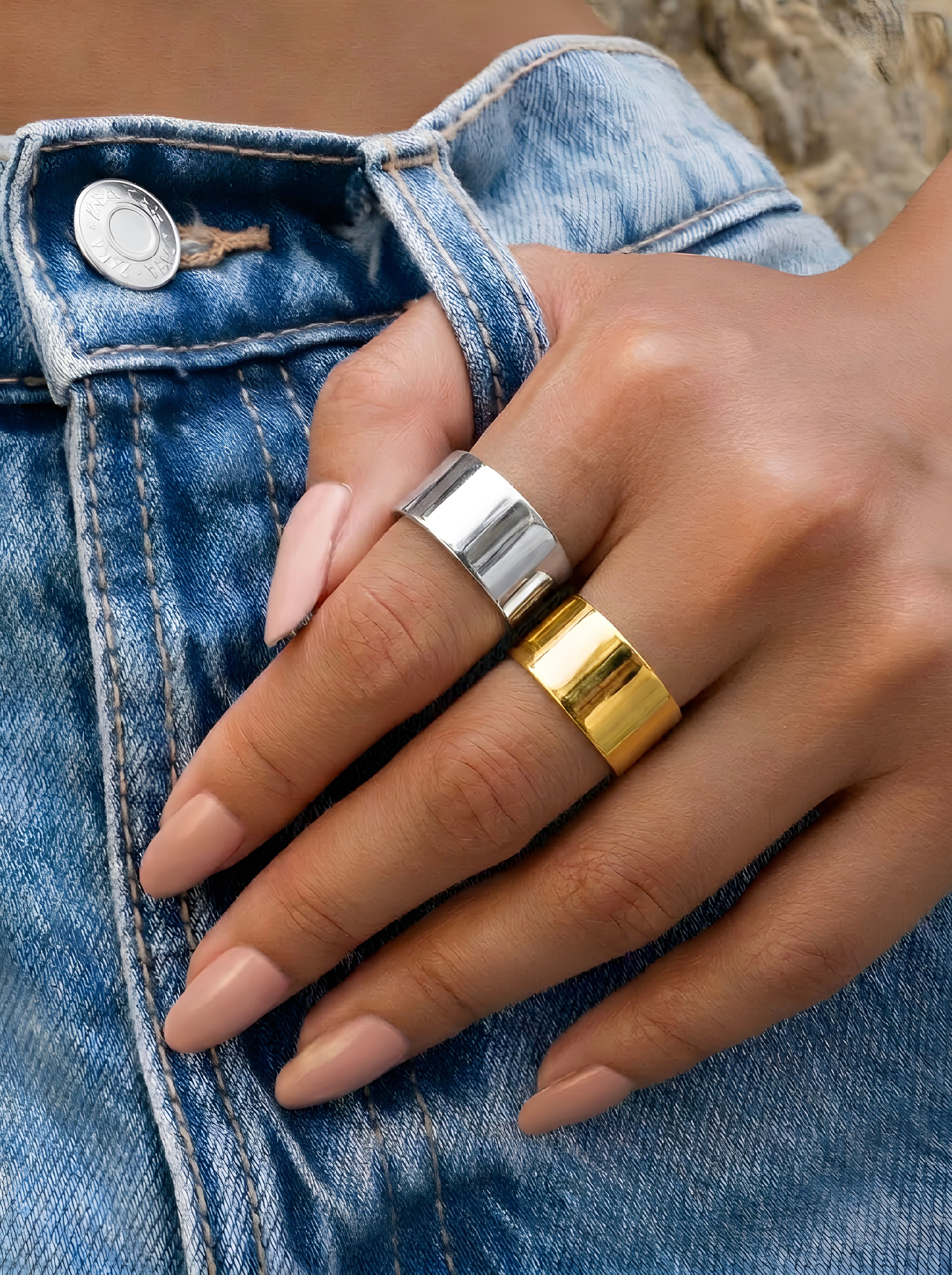 Close-up of gold wide band ring cuff worn on finger with polished mirror-like finish.