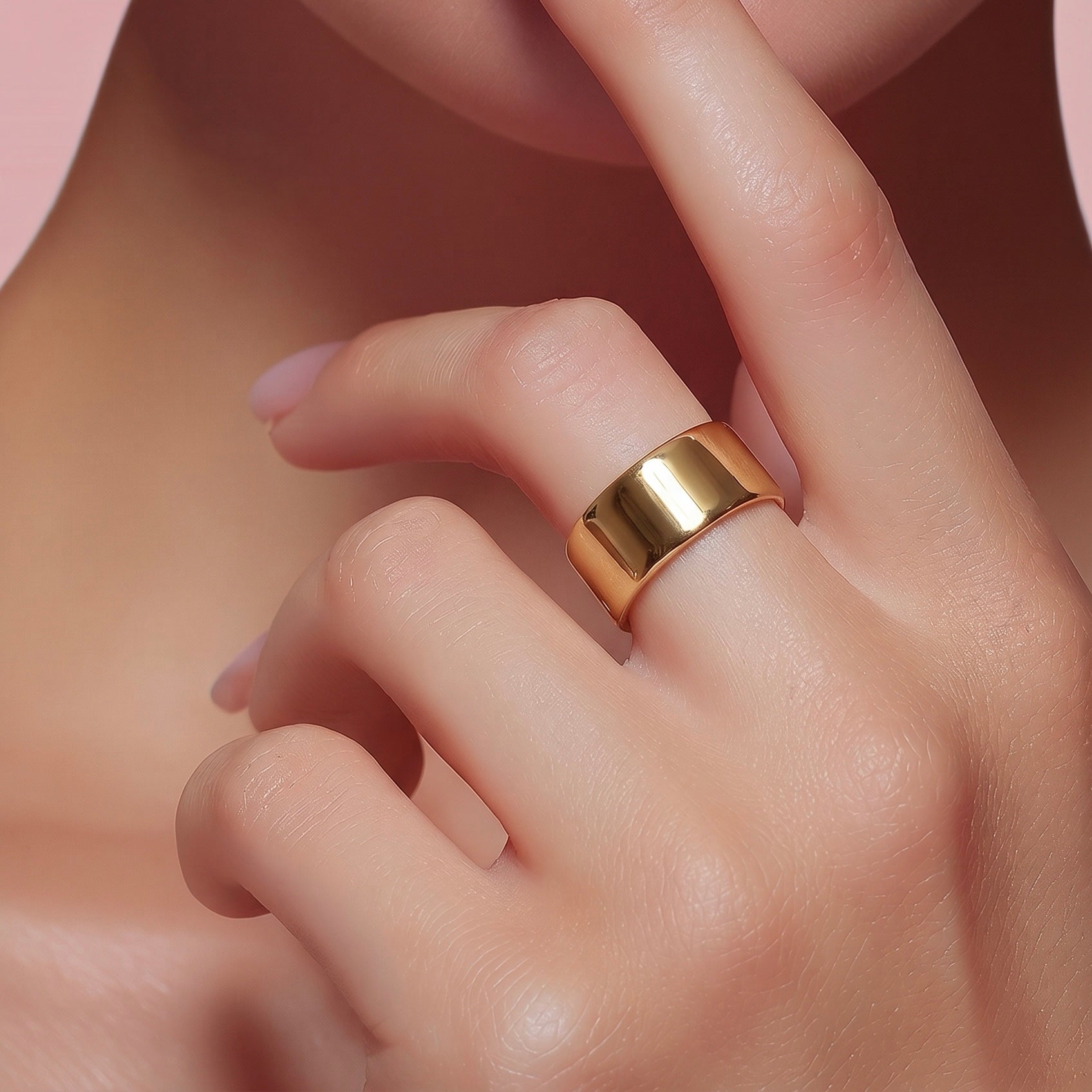 Close-up of gold wide band ring cuff worn on finger with polished mirror-like finish.