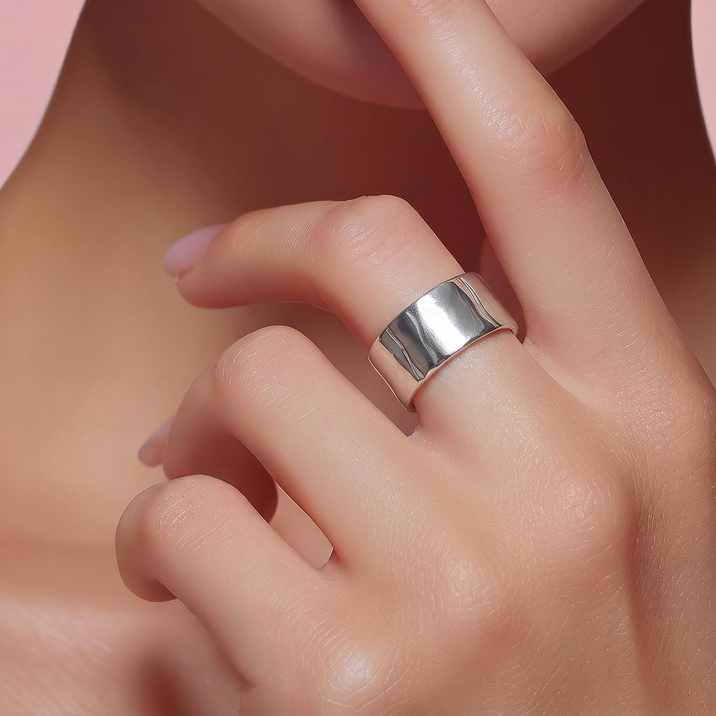 Close-up of platinum wide band ring cuff worn on finger with polished mirror-like finish.