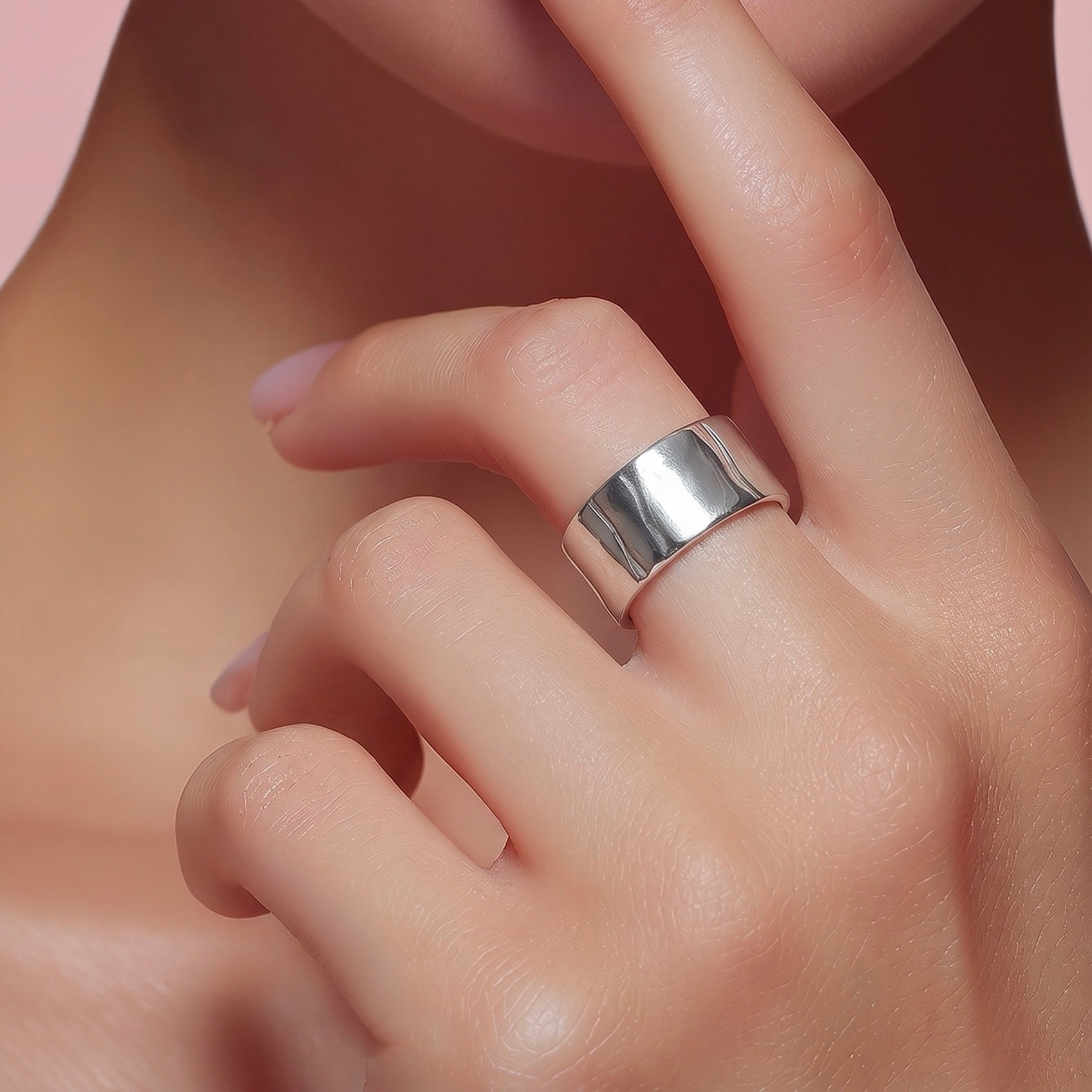 Close-up of platinum wide band ring cuff worn on finger with polished mirror-like finish.