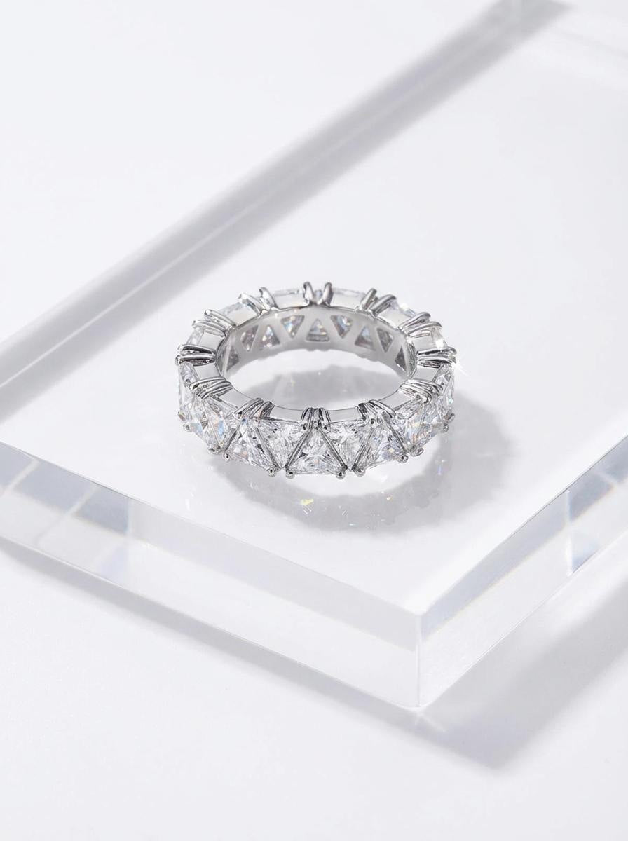 Silver ring with geometric triangle or stones displayed on clear acrylic surface