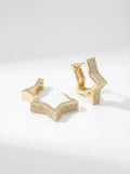 Gold star huggie earrings with zirconia detailing on a white background