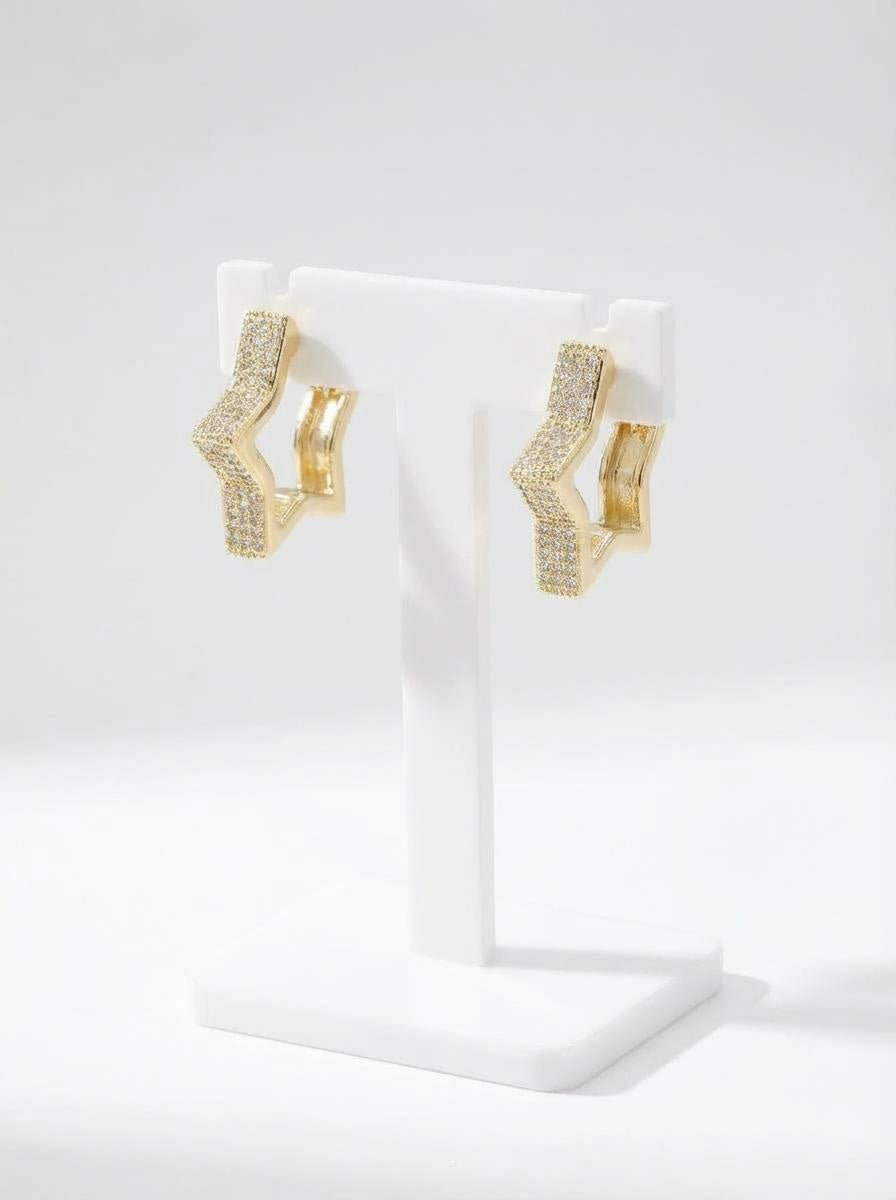 Gold star huggie earring with zirconia accents displayed on a jewellery stand