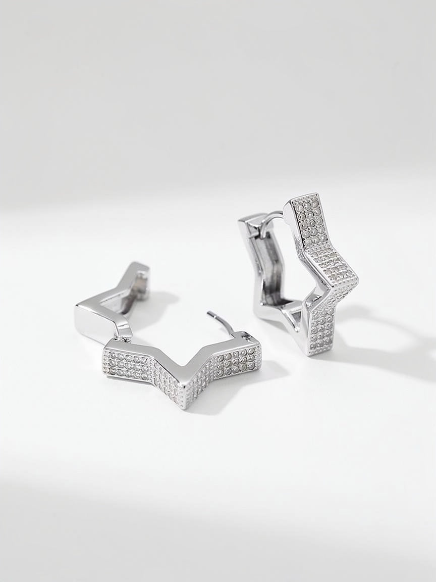 Silver star huggie earrings, with detailing on a white background