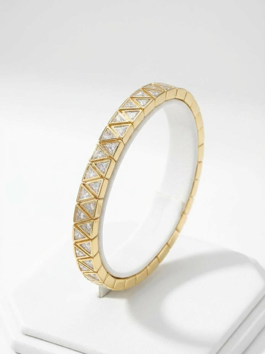 Gold stretch bracelet with clear triangular cubic zirconia stones, photographed on white background