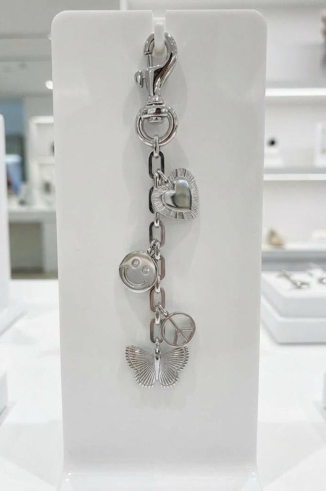 Rhodium tone, charms displayed on a jewelry, stand with heart, smile face, peace symbol, and butterfly accent