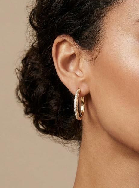 Model wearing 14K gold-plated pavé hoop earrings with cubic zirconia accents