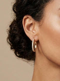 Model wearing 14K gold-plated pavé hoop earrings with cubic zirconia accents