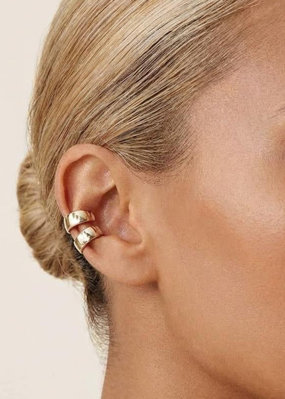 Model wearing gold-plated sterling silver huggie ear cuffs layered along the ear cartilage