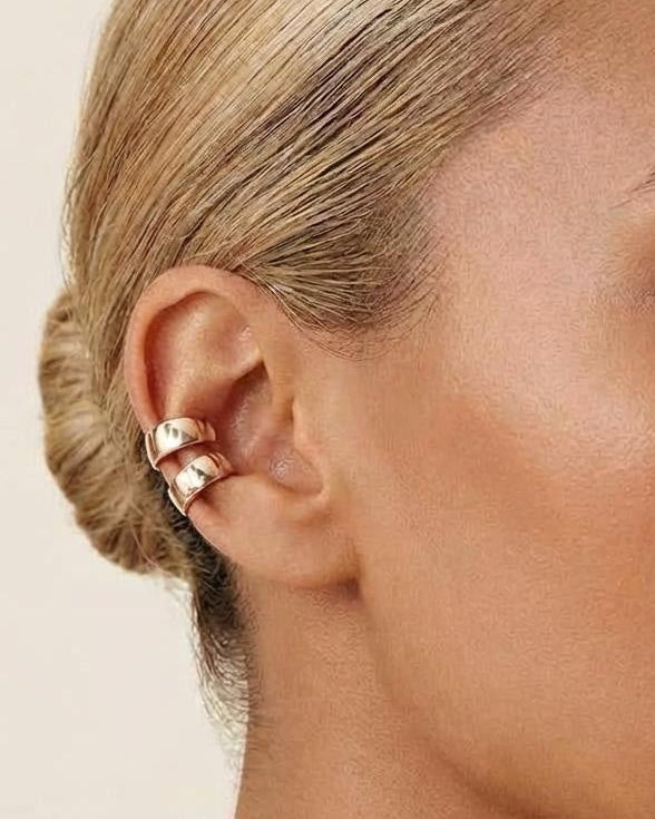 Model wearing gold-plated sterling silver huggie ear cuffs layered along the ear cartilage