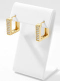 Close-up of gold square huggie hoop earrings with embedded cubic zirconia