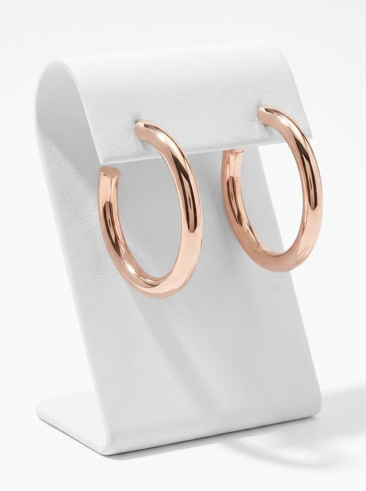 Rose gold hoop earrings photographed on minimalist jewelry stand