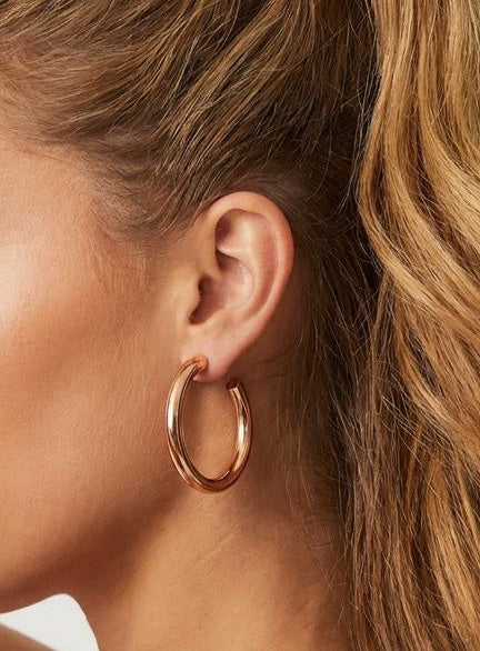 Model wearing medium-size 14K rose gold plated hoop earrings with hair pulled back