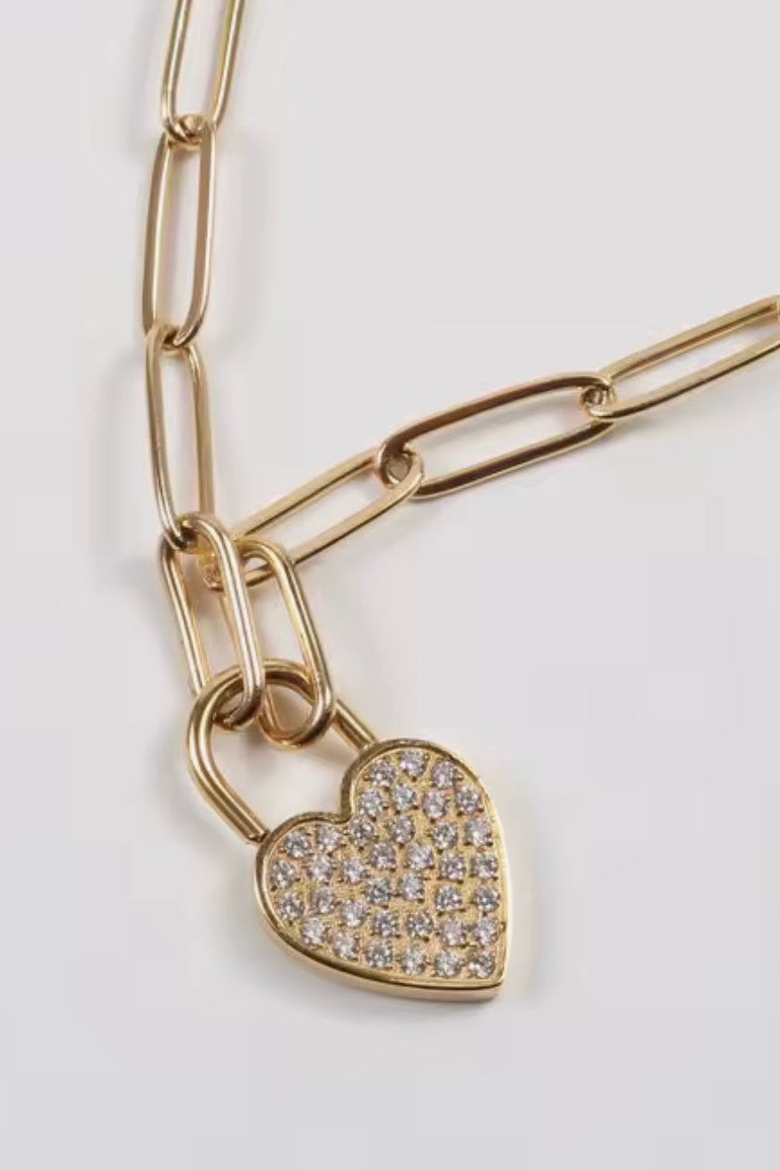 Gold chain necklace with a heart-shaped pendant on a light gray background
