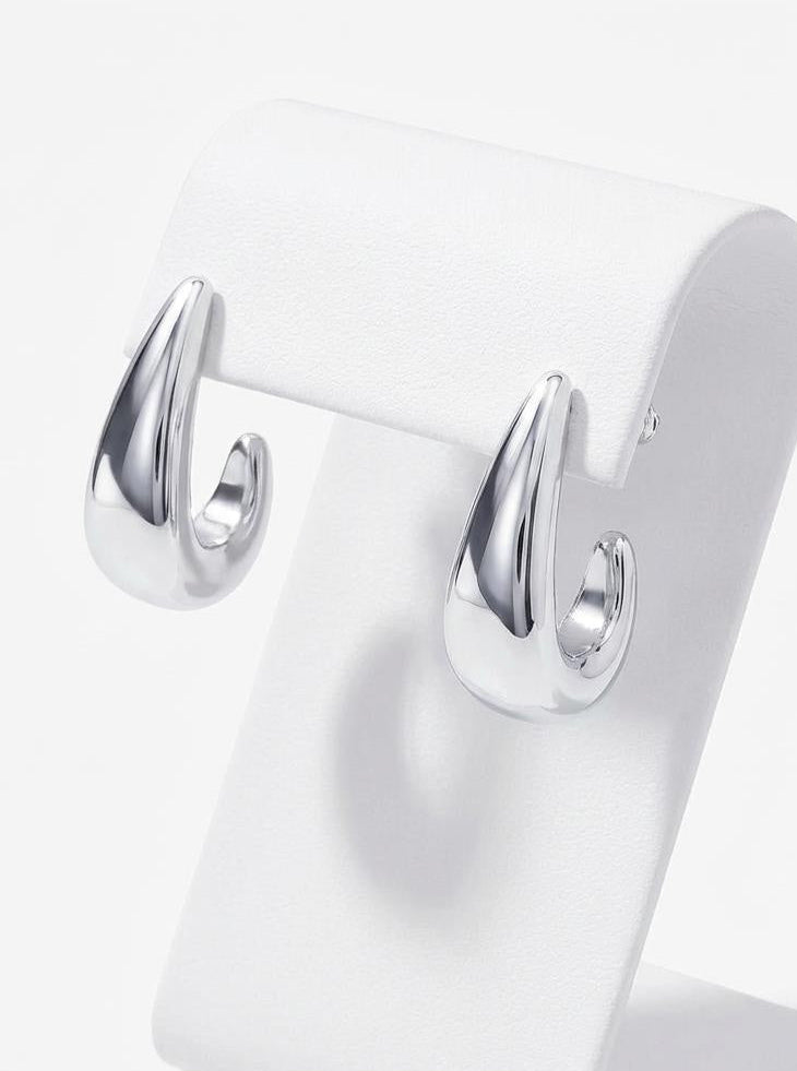 Silver earrings on a white stand against a white background