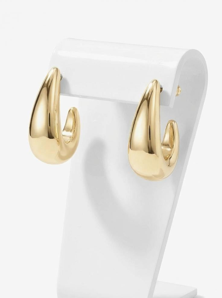 Gold hoop earrings on a white stand against a white background