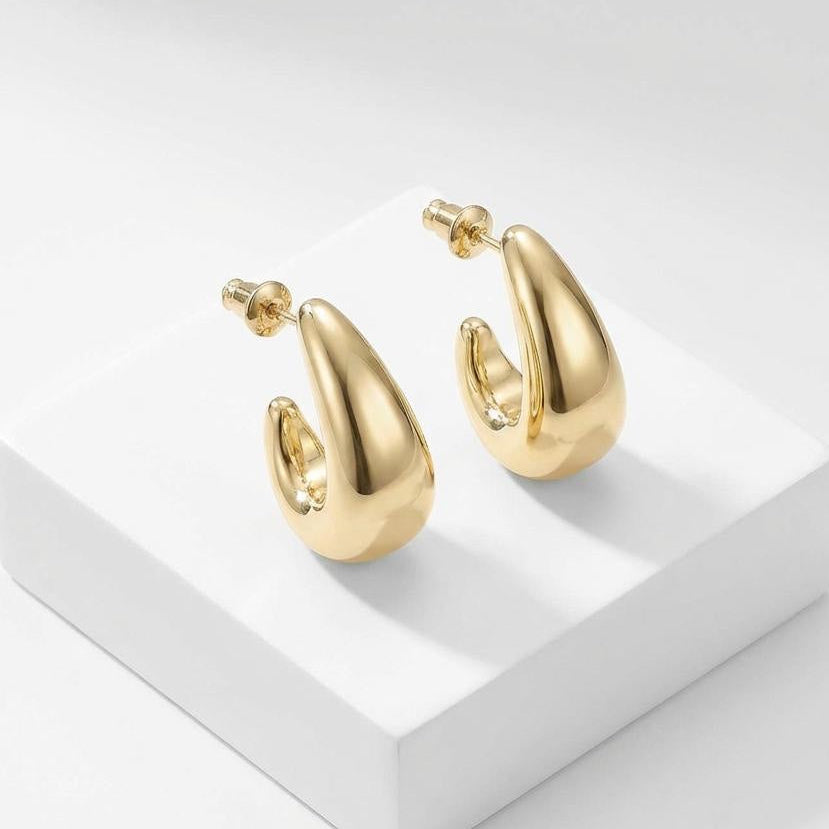 Gold hoop earrings on a white platform