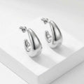 Silver hoop earrings on a white platform
