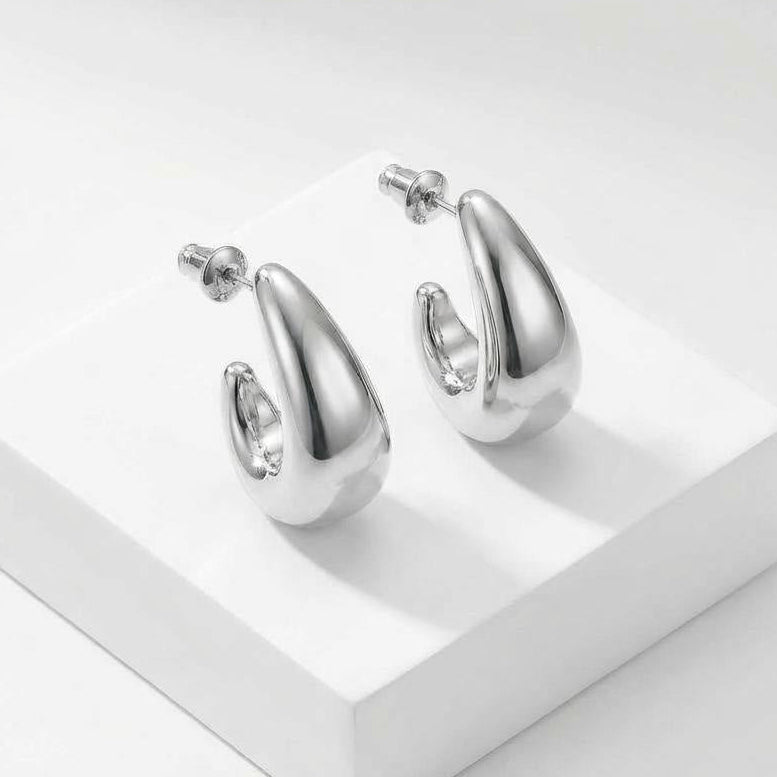 Silver hoop earrings on a white platform