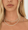 Close-up of a woman wearing a silver necklace with measurements indicated.