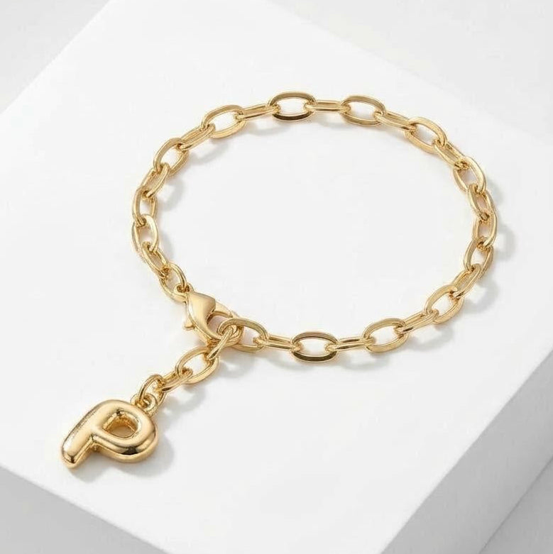 Gold chain initial bracelet with a heart charm on a white background