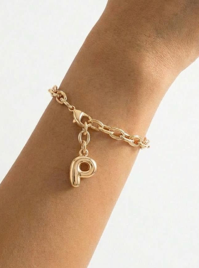 Gold bracelet with a letter charm on a wrist