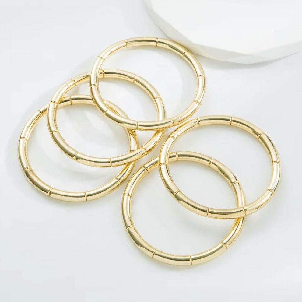 Set of gold bangle bracelets on a white background
