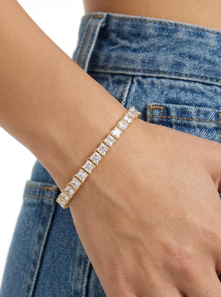 Gold-plated tennis bracelet with square cubic zirconia stones worn on wrist