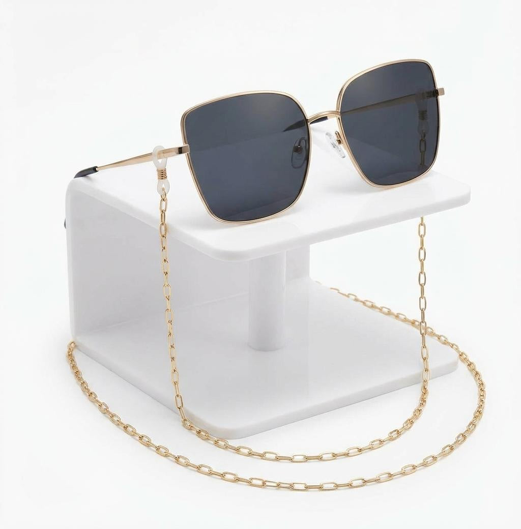 Sunglasses with a gold chain on a white stand