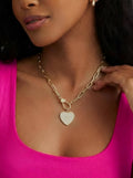 Woman wearing a gold chain necklace with a pavé heart pendant