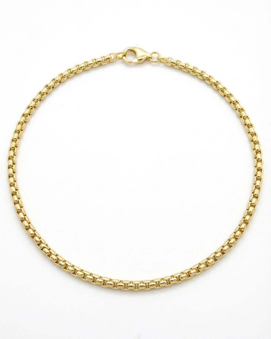 Gold chain ankle bracelet on a white background