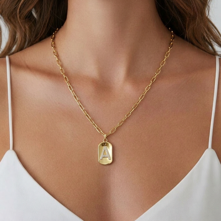 Gold initial charm pendant necklace with cubic zirconia letter on delicate gold chain worn by model
