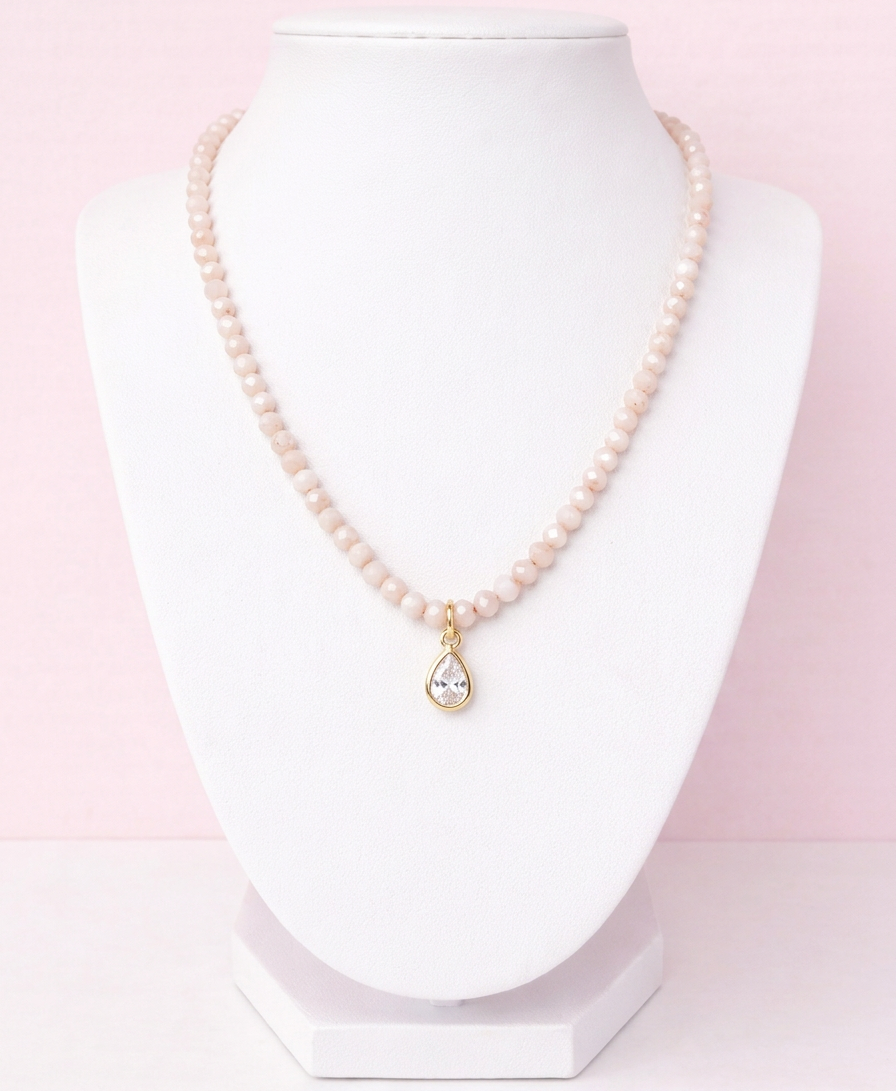 Iridescent apricot colored glass bead necklace with gold teardrop crystal pendant on delicate chain