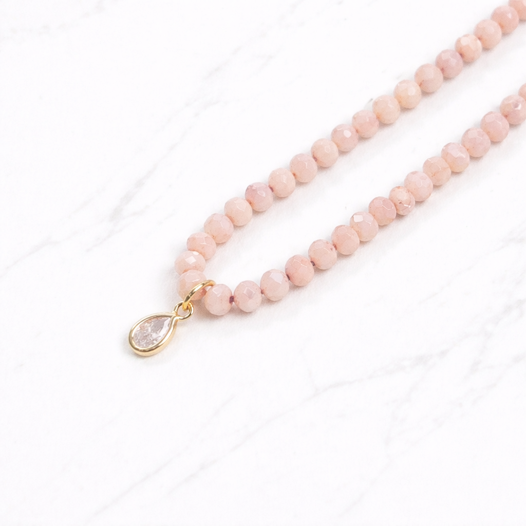 Iridescent apricot colored glass bead necklace with gold teardrop crystal pendant on delicate chain