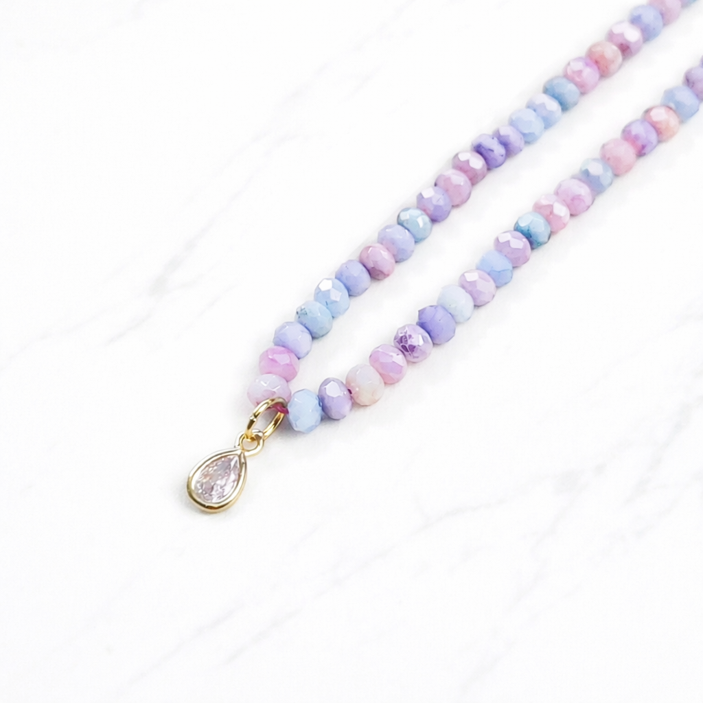 Iridescent purple glass bead necklace with gold teardrop crystal pendant on delicate chain